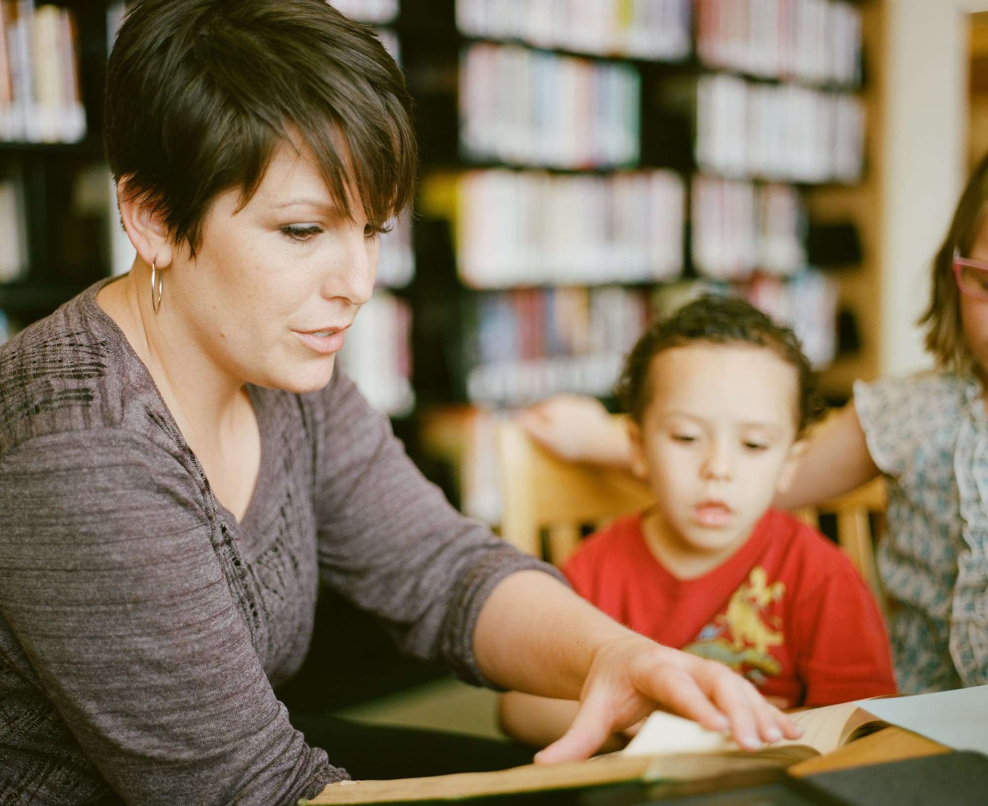 Woman sitting with a child at a desk with books